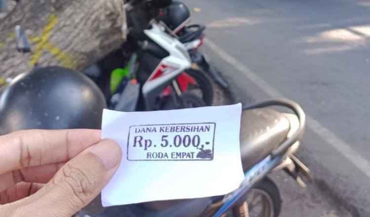 Salah seorang pengunjung wisata Pantai Watu Dodol Banyuwangi menunjukkan kertas parkir diduga ilegal. (Foto: Endang / zonaindonesia.co.id)