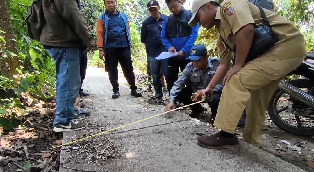 Anggota DPRD Jember dan tim sidak mengukur lebar jalan rabat beton di Dusun Lengkong Toko. (Foto: Zainul Hasan)