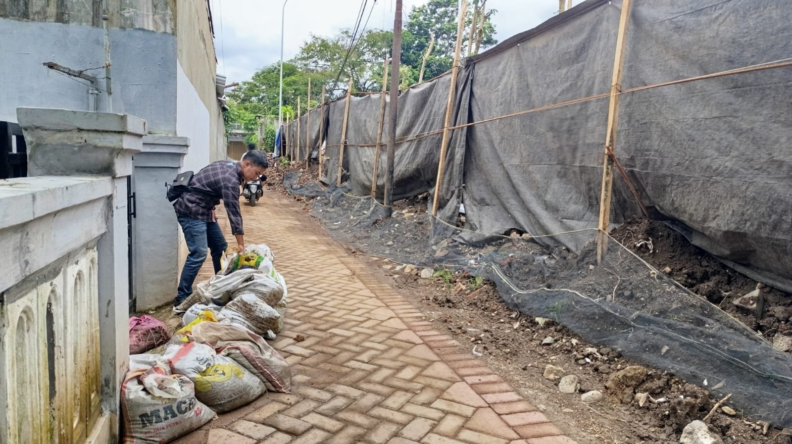 Warga Kelurahan Patrang memasang tanggul di depan rumah untuk mengantisipasi banjir. (Foto: Teamwork)