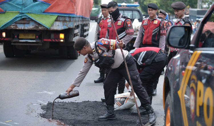 Anggota Polres Situbondo menambal jalan berlubang, Rabu (19/2/2025). (Foto: Fathur Rosi/zonaindonesia.co.id)