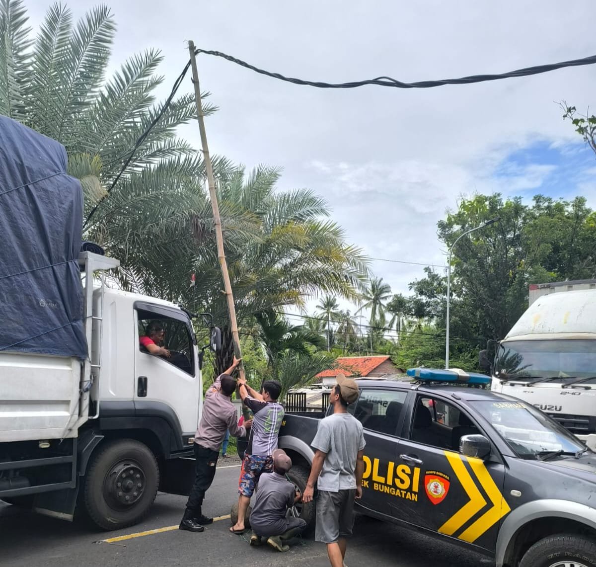 Warga dan polisi menyangga kabel listrik yang melintang hingga mengganggu pengguna jalan. (Foto: Humas Polres Situbondo)
