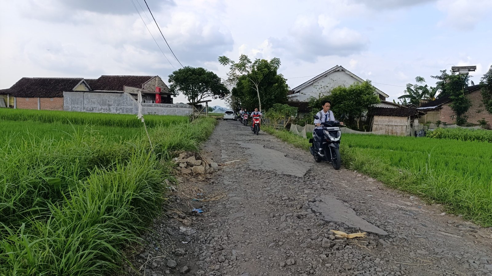 Siswa SMP melintas di jalan rusak Dusun Gumuk Suda, Senin (14 April 2025). (Foto: Zainul Hasan/zonaindonesia.co.id)