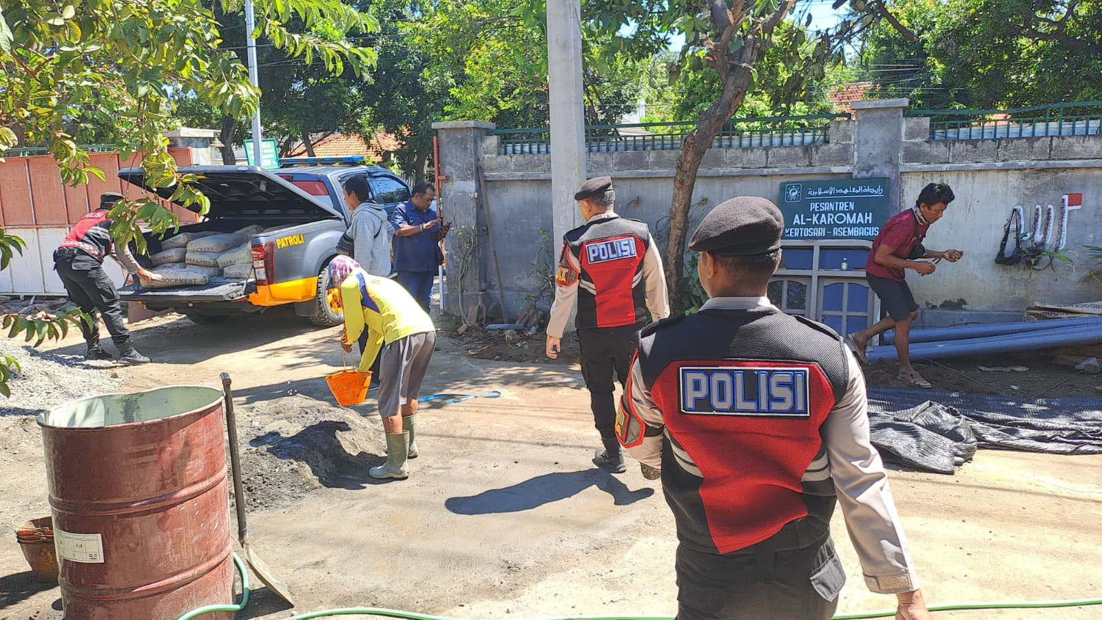 Personel Samapta Polres Situbondo mengantarkan semen ke Ponpes Al-Karomah. (Foto: Teamwork)