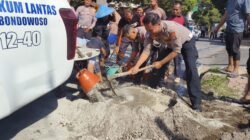 Anggota Polres Bondowoso mengaduk pasir untuk menambal jalan berlubang. (Foto: Humas Polres)