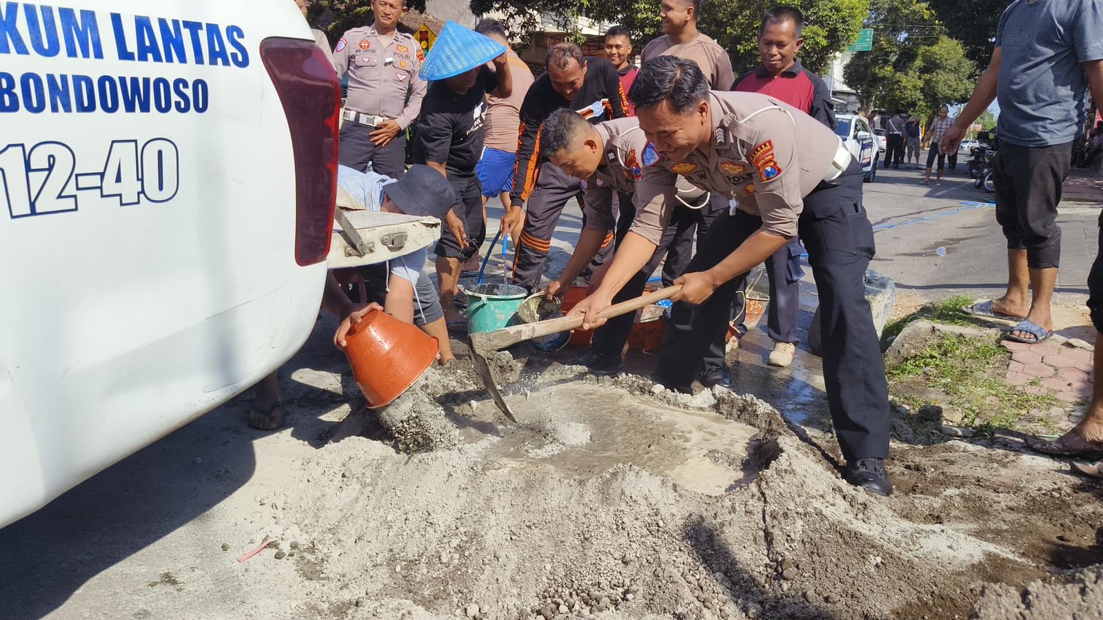 Anggota Polres Bondowoso mengaduk pasir untuk menambal jalan berlubang. (Foto: Humas Polres)