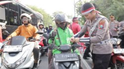 Anggota Polrestabes Surabaya membagikan bendera merah putih kepada pengendara. (Foto: Humas Polres/Dok)