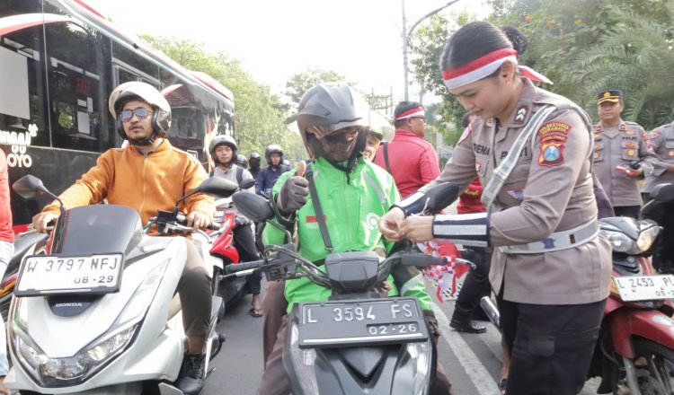 Anggota Polrestabes Surabaya membagikan bendera merah putih kepada pengendara. (Foto: Humas Polres/Dok)